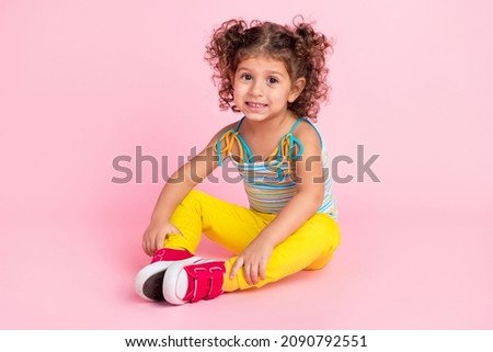 Portrait of attractive cute cheerful wavy-haired girl sitting on floor spending time isolated over pink pastel color background