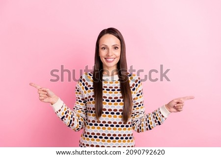Photo of pretty charming young woman wear dotted sweater smiling pointing two fingers empty space isolated pink color background