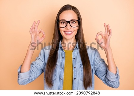 Photo of cheerful smiling lady showing okay gesture wear glasses denim casual shirt isolated on beige color background