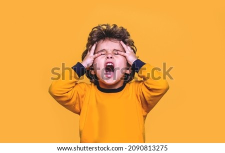 Cute little child boy shout with hands on head. Kid feel strain, angry, bored isolated on yellow background.