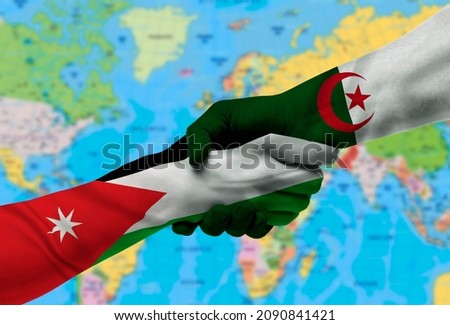Handshake between Algeria and Jordan flags painted on hands.With background of world map
