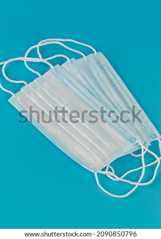 Four new medical surgical facial three-layer masks lie side by side on a blue background