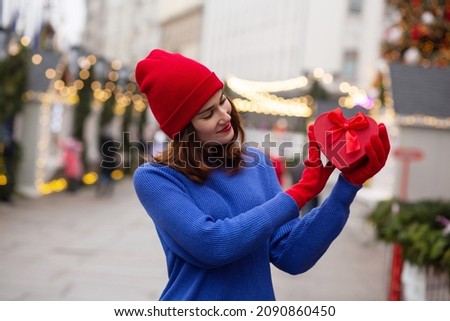 Adorable young woman holding gift in a box at the Christmas fair