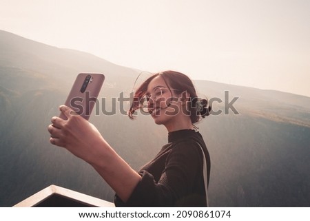 Young beautiful woman traveler looking at sunset, taking a selfie and beautiful landscape with a lookout point. Mental health relax and thinking about the future. Freedom, travel, vacation. Copy space