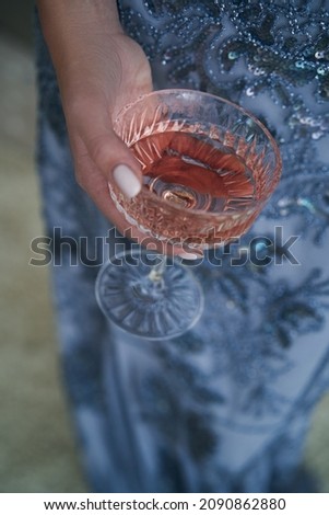 girl on a light carpet in an elegant blue dress with a glass in her hands