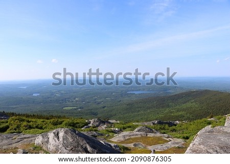 Mountain range view with lakes in summer New England area with green trees and blue mountain with large blue lake rocks in foreground depth of massive wide expansive adventurous beautiful nature