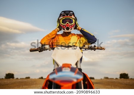 Portrait of motocross rider taking off helmet Royalty-Free Stock Photo #2090896633