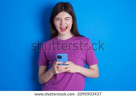 Caucasian woman wearing purple T-shirt isolated over blue background taking a selfie  celebrating success