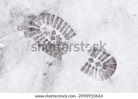on the freshly fallen snow, the imprint of the sole of winter shoes with a large pattern that ensures safe movement on snow-covered and icy sidewalks, selective focus Royalty-Free Stock Photo #2090910664