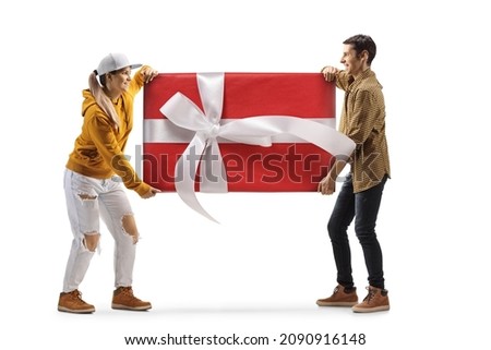 Full length profile shot of a young man and woman carrying a big wrapped present isolated on white background