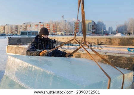 Worker assembler in jacket and black hat unloads ice blocks