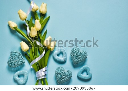 Valentine's day concept with blue hearts and bouquet of white tulips on light blue background. Mock-up for holiday card - birthday, father's day, valentine's day. Top view with copy space