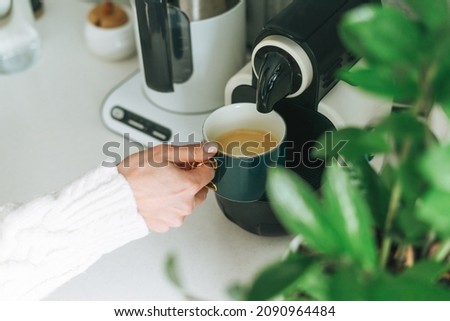 Crop photo of young woman pours coffee from coffee machine in kitchen at home