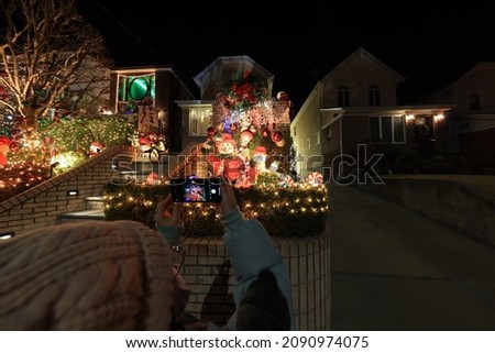 Visitors take photos of the holiday lights and Christmas decorations of homes in the Dyker Heights section of Brooklyn in New York City on Tuesday, December 14, 2021. (Gordon Donovan)