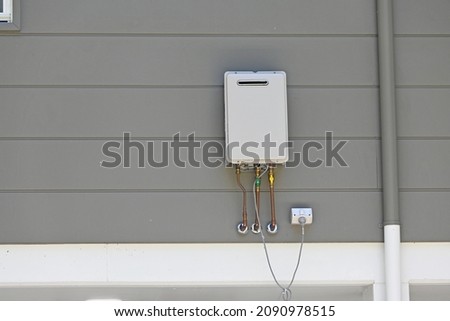 Instantaneous gas hot water heater on the side of a house  Royalty-Free Stock Photo #2090978515