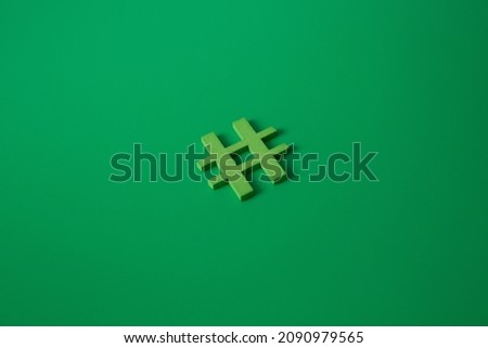 Green wooden symbol Hashtag "#" on green background and copy space for social media educational concept