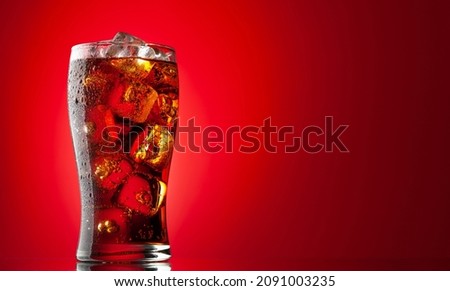 Cola with ice. Fresh cold sweet drink with ice cubes. Over red background with copy space Royalty-Free Stock Photo #2091003235