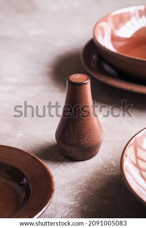 Salt shaker and Empty ceramic tableware, bowls and plates on a pink background. Group of ceramic tableware. Selective focus. Textured object. Copy space.