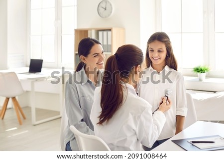 Happy mother and daughter seeing medical specialist. Family doctor listening to child's breathing or heartbeat. Friendly pediatrician using stethoscope to check lungs or heart of her little patient Royalty-Free Stock Photo #2091008464