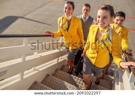 Smiling airline workers walking up airplane stairs Royalty-Free Stock Photo #2091022297