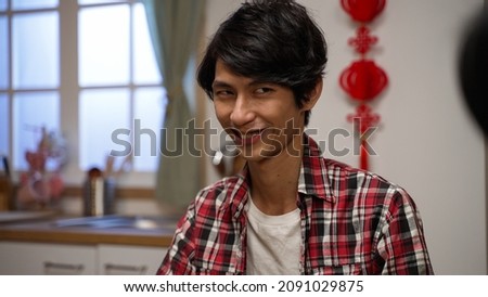 closeup of a scheming son man plaid shirt looking around at his components with cunning smile on face in mahjong game on chinese lunar new year's eve at home Royalty-Free Stock Photo #2091029875