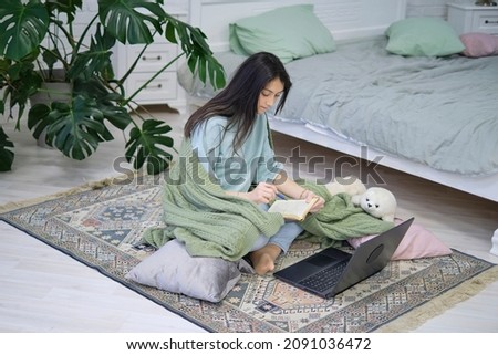 Teenage girl doing homework in the bedroom on the floor. teen girl school student write notes watch video online webinar learn on laptop. distance learning course video conference pc call.