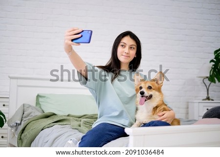 Teenage girl taking selfie with her dog at home. Dog lover with domestic animal. Modern technology, people and animals concept