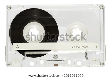 Transparent plastic case of vintage audio cassette for replaying music with black tape and inscription on white background of light studio
