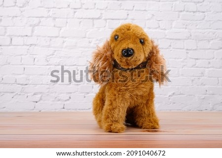 Animal toy : Dog brown doll put on the wooden table with White brick wall