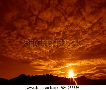 Dramatic Sky with a Black Mountain Silhouette in foreground, Play of Light and Shadow. sun set above horizon line.  