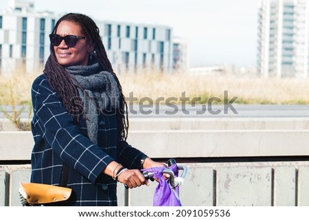 African american woman holding a bike with cool style on urban background in winter. Copy-space