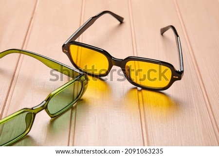 Different modern sunglasses on color wooden background, closeup