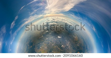 Aerial view from airplane window at high altitude of little planet distant city covered with layer of thin misty smog and distant clouds in evening Royalty-Free Stock Photo #2091066160