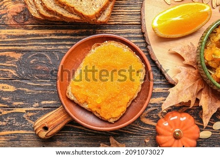 Plate with tasty bread and pumpkin jam on table