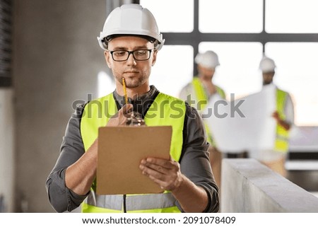 architecture, construction business and building concept - thinking male architect in helmet and safety west with clipboard working at office Royalty-Free Stock Photo #2091078409