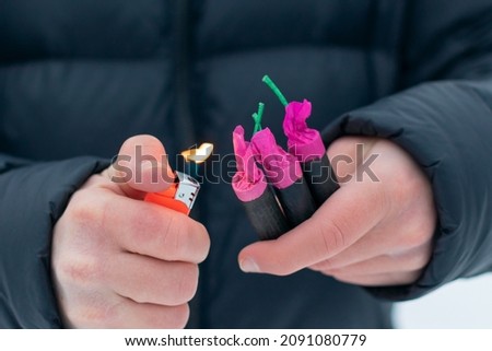 Guy Sets Fire to the Flash Noise Firecrackers Outdoors in Winter at Daytime. Loud and Dangerous New Year's Entertainment. Hooliganism with Pyrotechnics. Noise of Petards in Public Places Royalty-Free Stock Photo #2091080779