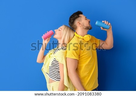 Couple drinking soda on color background Royalty-Free Stock Photo #2091083380
