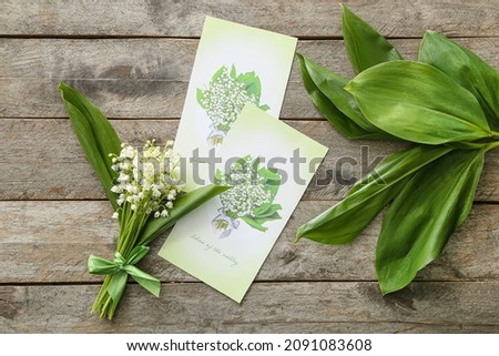Beautiful lily-of-the-valley flowers and greeting cards on wooden background