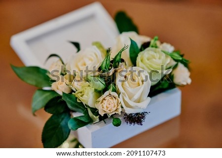 delicate arrangement in a box with live roses and rings of the newlyweds for the ceremony