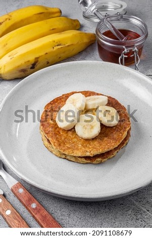 Banana oat pancakes topped with sliced ​​bananas and honey.