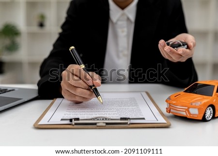 Car rental company employees are checking the contract before sending the car to the customer to rent the car, preparing the contract for the customer to sign the rental agreement. Car rental concept.