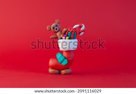 plasticine homemade figure, boot with gifts, symbols of Christmas and New Year on a red background