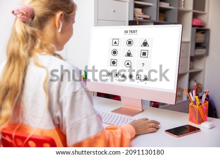 Girl studying at home and taking IQ test on computer