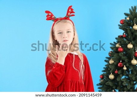 Cute little girl on blue background with Christmas tree