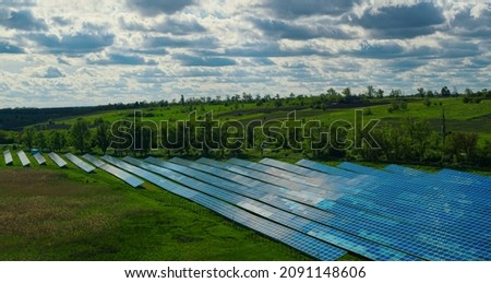 Drone shot solar batteries in green field. Sun panels park. Alternative energy source. Blue solar panels farm. Sustainable energy factory. Alternative power plant. Sunlight renewable energy concept