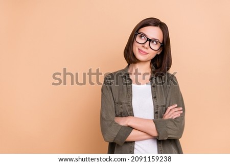 Photo of curious lady folded hands look empty space wear eyeglasses khaki shirt isolated beige color background