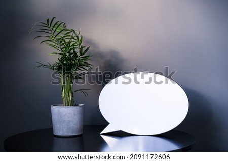 Empty blank lightbox with space for text , small Areca Palm home plant in a concrete pot on black table with dark gray wall background. Mockup. Modern minimalist interior design. Selective focus