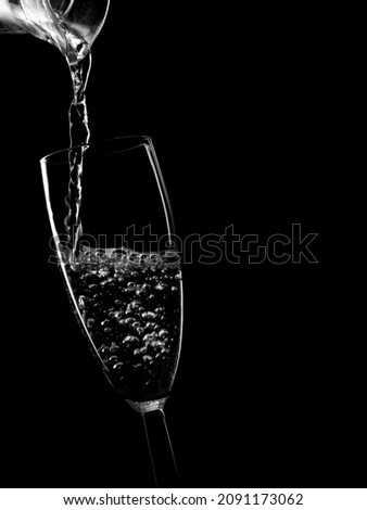 Pouring water, clear drink into aglass, monochrome black and white.