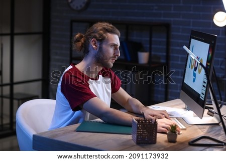 Handsome man using computer at home late in evening