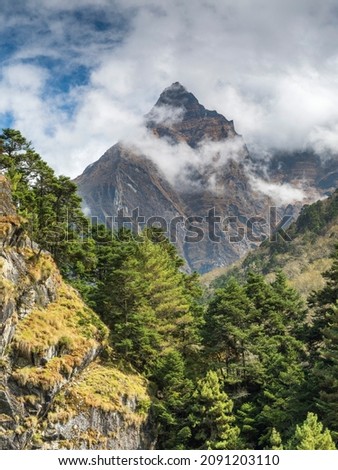 view from valley to triangle summit in clouds in sunny day in Nepal